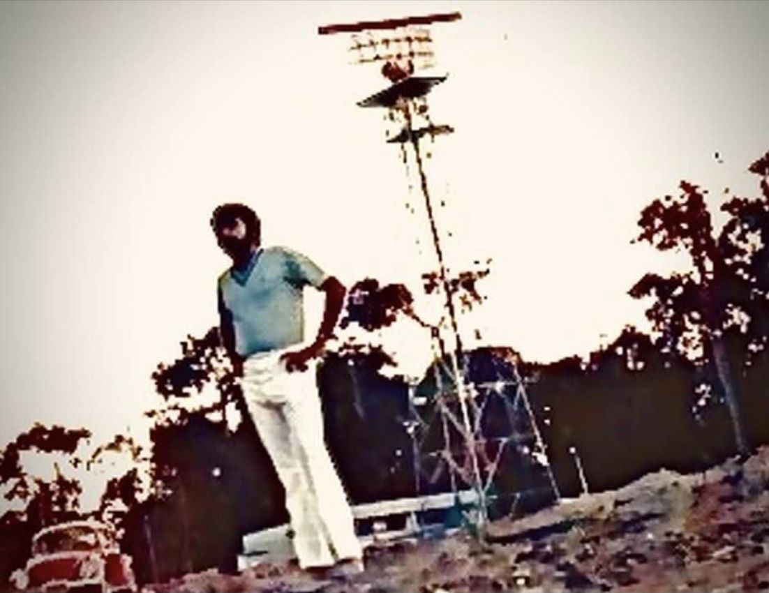 A young Juan Xuna standing in front of a radar antenna tower
