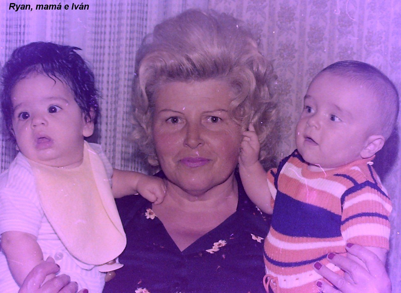An older woman holding two babies; the photo is labelled Ryan, mamá e Iván